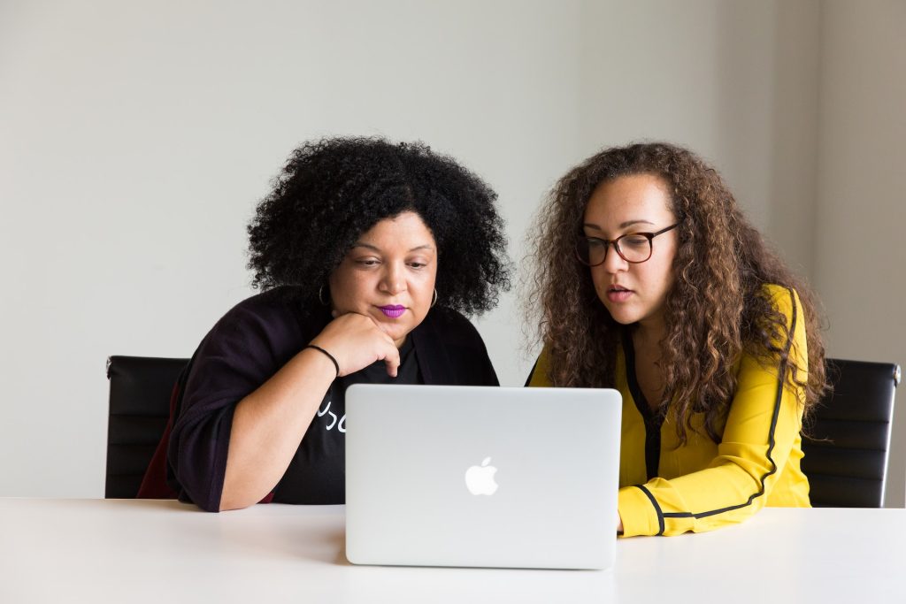 Foto de duas mulheres usando um MacBook, ilustrando a ideia de supervisão de estágio