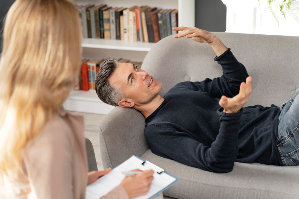 Homem na terapia explicando para a psicanalista o significado de seu sonho que o deixa com ansiedade.