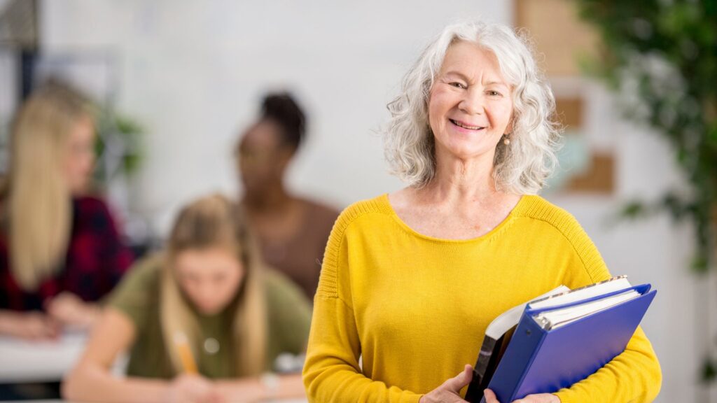 senhora idosa mostrando a prática da educação contínua, segurando livros e cadernos